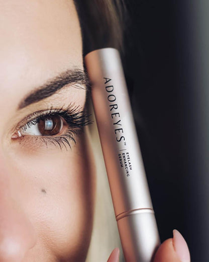 Close up of a woman holding Adoreyes Eyelash Serum beside her eye