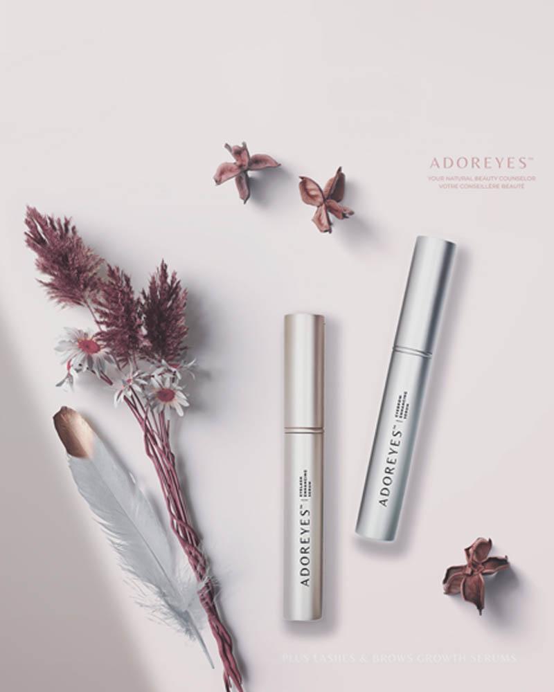 Adoreyes eyelash and eyebrow serum tubes on a pink floral background